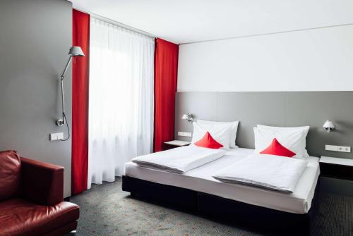 斯图加特Vienna House Easy by Wyndham Stuttgart的一间卧室配有一张带红色枕头的床和一把椅子