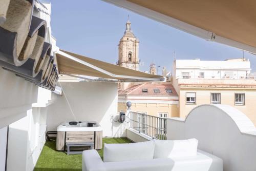 马拉加THE CLOCK HOUSE Luxury Urban Suites的阳台配有白色家具,享有建筑的景致。