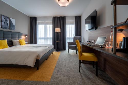 雷根斯堡Hotel INCLUDiO的酒店客房配有一张床、一张书桌和一台笔记本电脑