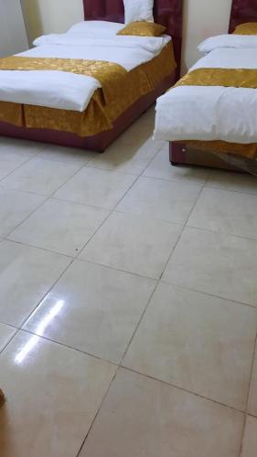 阿尔阿尔غرف مجهزة سكن وتجارة عرعر رجال فقط的两张床位于白色瓷砖地板上。
