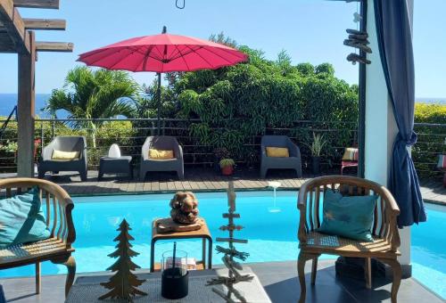 圣皮埃尔Suite INDIGO JACUZZI PRIVE PISCINE VUE MER acces cuisine laverie的一个带两把椅子和红伞的游泳池