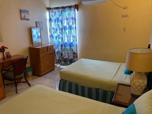 CanaanShirvan Holiday Apartments One Bedroom的一间卧室设有两张床、一张桌子和一个窗口。