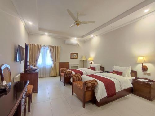 伊斯兰堡Welcome Hotel Islamabad的酒店客房,配有两张床和两把椅子