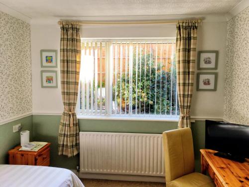 科尔斯希尔Blythewood Guest House的一间卧室设有一张床、一个窗口和一把椅子