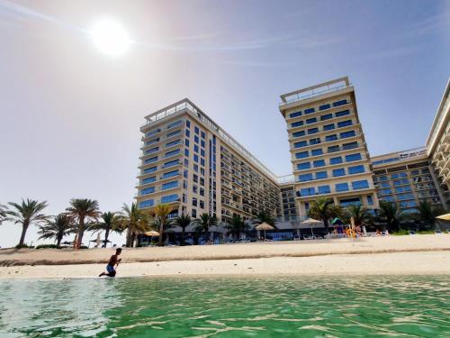 拉斯阿尔卡麦Luxurious Studio Pacific Al Marjan Island - beachfront property的站在海滩上两栋建筑前的人
