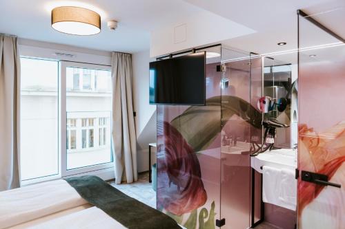 林茨ART-INN Design Self-Check-in-Hotel的一间卧室设有一张床,玻璃墙上配有电视