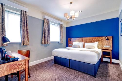 沃金The Wheatsheaf by Innkeeper's Collection的蓝色卧室配有一张床和一张书桌