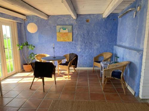 LöderupStrandbadsgården B&B的配有桌椅和蓝色墙壁的客房