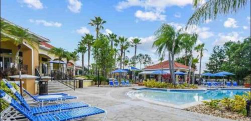 基西米Terra Verde Resort的度假村的游泳池,配有蓝色的椅子和遮阳伞