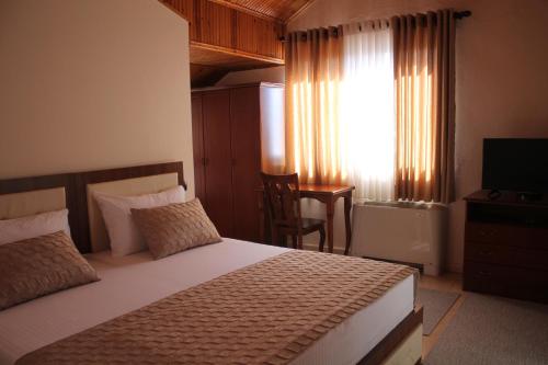 Mjedë哈斯米加酒店的一间卧室配有一张床、一台电视和一个窗口