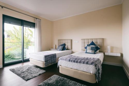 丰沙尔Casa Branca的一间卧室设有两张床和大窗户