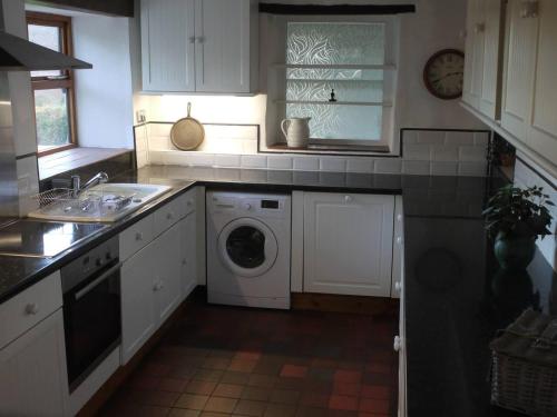 HirnantTranquil 3-Bed Cottage Near Lake Vyrnwy的厨房配有白色橱柜、洗衣机和烘干机