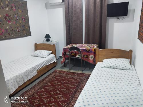 布哈拉Hotel Mosque Baland的一间设有两张床、一张桌子和一张地毯的房间