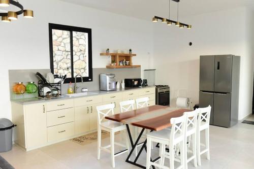 ‘Ein el Asadממלכת החלומות - וילה מושלמת עם ממ"ד בריכה פרטית ונוף גליל的厨房配有木桌和冰箱。