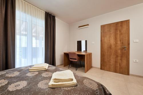 维帕瓦Posestvo Rouna - winery and apartments的一间卧室配有一张床、一张书桌和一个窗户。