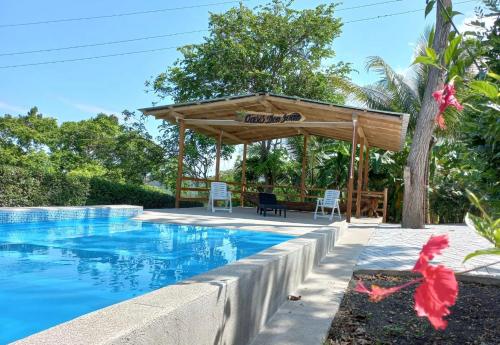 Don JuanL'Oasis Don Juan的一座带木凉亭的游泳池位于一座房子旁边