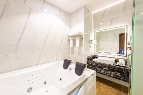 塞卡凯Le Park Concord - Sakaka的白色的浴室设有浴缸和大镜子