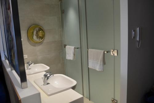 马尼拉Luxxe interior design condo @ Novotel Suites Manila - Acqua的浴室设有2个盥洗盆和带镜子的淋浴。