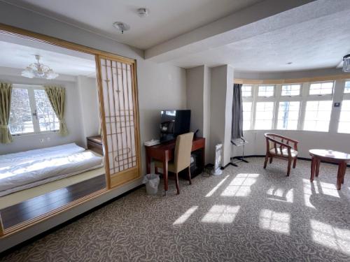IidaHakuba Sun Valley Hotel Annex - Vacation STAY 90355v的酒店客房配有书桌、床和桌子。