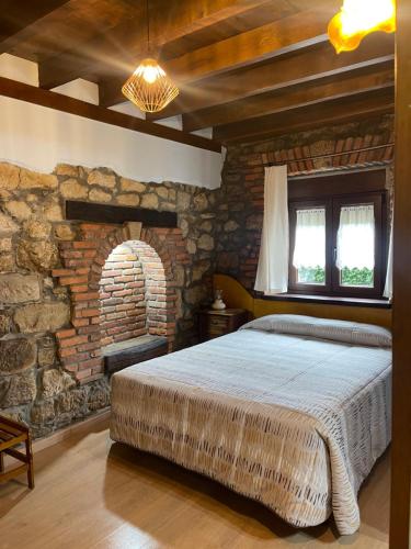 桑提亚纳德玛Posada La Llosa de Viveda - Adults Only的一间卧室设有一张大床和石墙