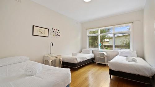 莱克斯恩特伦斯码头小路海滩度假屋的一间卧室设有两张床和窗户。