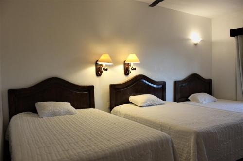 瓦哈卡市安缇格福廷酒店的一间设有两张带白色床单和灯具的床的客房