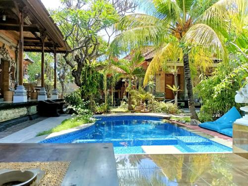 珀尼达岛Green Palace Homestay的棕榈树房子后院的游泳池
