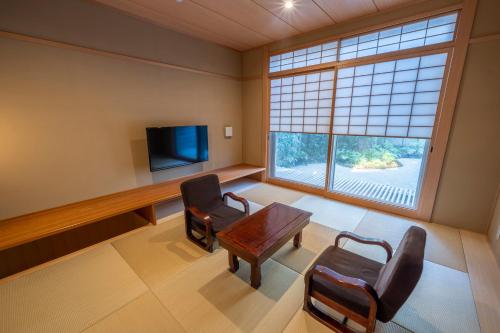 京都RESI STAY Jisco Hotel Kyoto Goshonishi的一间设有桌椅和电视的等候室