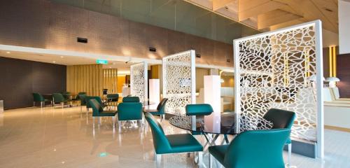 新加坡二号航站楼大使过境休息室酒店的一间设有绿色椅子和桌子的等候室