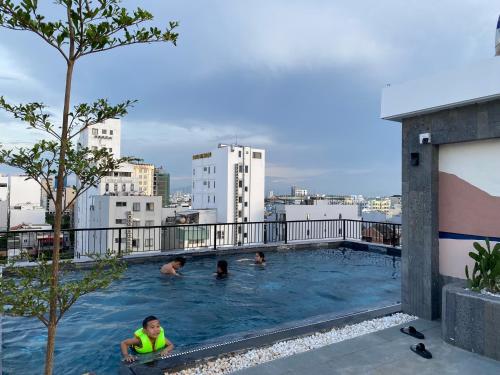 岘港LAGOM APARTMENT AND HOTEL的一群人在一座大楼的游泳池里