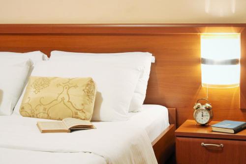 贝尔格莱德雷克斯酒店的一间卧室,配有一张带时钟和书籍的床