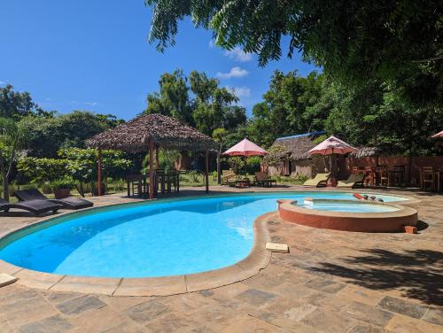 迭戈苏瓦雷斯Hotel Lakana Ramena的庭院内的游泳池,配有椅子和遮阳伞