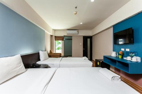 曼那Solace at Srinakarin Hotel的一间酒店客房,设有两张床和电视