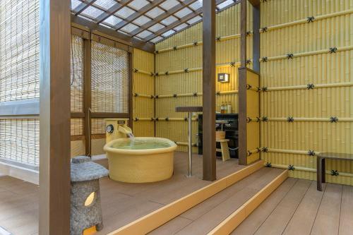 京都ManyonoyuHotelKyotoEminence的一间带浴缸的浴室,位于一间拥有黄色墙壁的客房