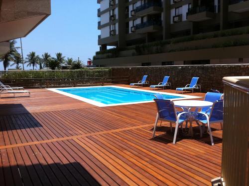 里约热内卢巴拉海滩最佳公寓的一个带椅子和桌子的游泳池