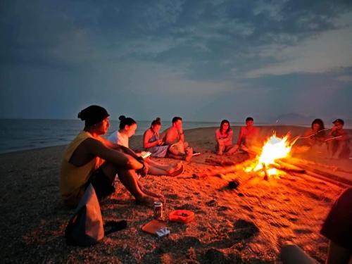 Ao LukKRABI BAMBOO KINGDOM at AOLUEK PARADISE的一群人坐在海滩上的火堆旁
