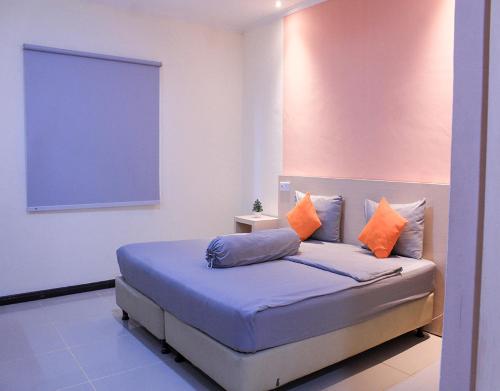 BagansinembahSuzuya Hotel Bagan Batu的一间卧室配有带橙色和蓝色枕头的床