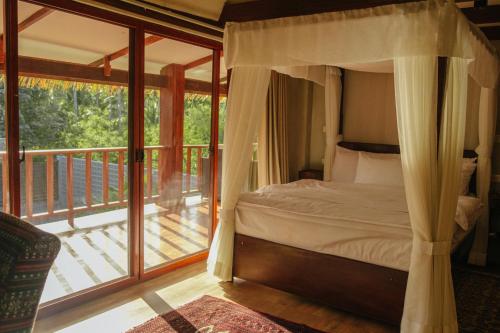 卢纳将军城Domu Mia Villa Siargao的一间卧室设有一张天蓬床和一个阳台