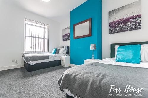 利Firs Serviced Accommodation的一间卧室设有蓝色墙和两张床