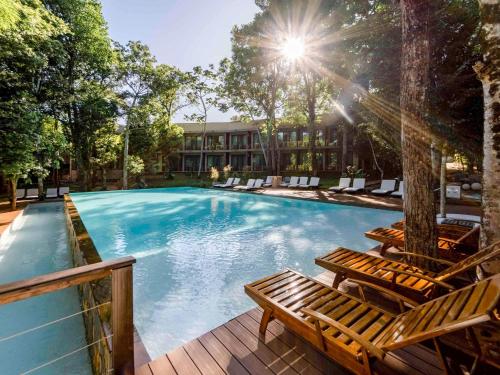 伊瓜苏港伊瓜苏美居伊露酒店的一个带两个长椅和房子的大型游泳池