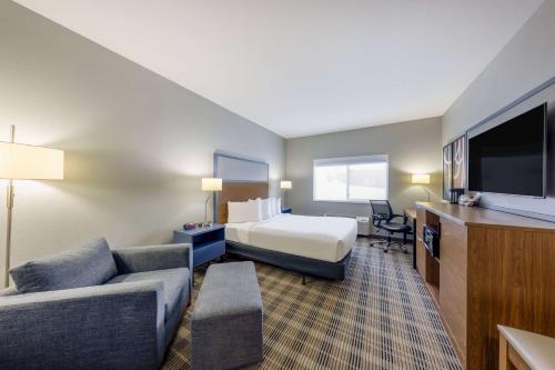 德卢斯AmericInn by Wyndham Duluth的酒店客房配有床、沙发和电视。