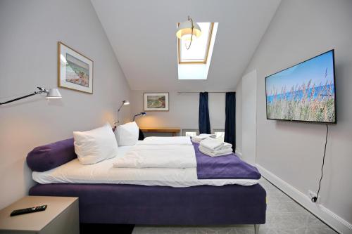 海利根达姆Villa Greif Wohnung 05的卧室配有一张床,墙上配有电视。