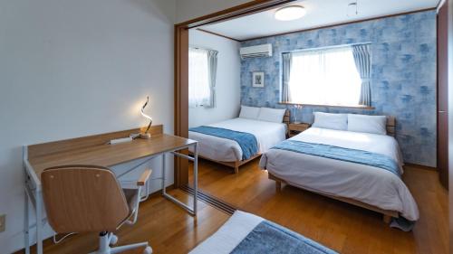 宫古岛红色之花度假屋的一间卧室配有两张床、一张桌子和一面镜子