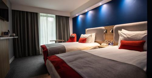 斯丹斯达蒙费雪特Holiday Inn Express London Stansted Airport, an IHG Hotel的酒店客房设有两张床和蓝色的墙壁。