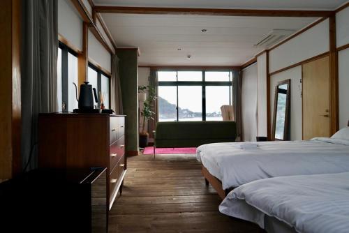 沼津Tagore Harbor Hostel的酒店客房设有两张床和窗户。
