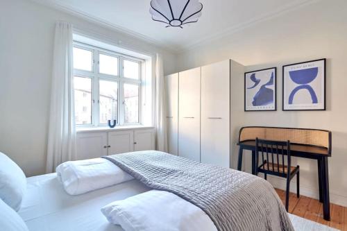 哥本哈根Large & Stylish Flats in Trendy & Vibrant Neighbourhood的一间卧室配有一张床、一张桌子和一个窗户。