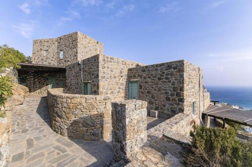 米克诺斯城Villa Azzuro II - Mykonianvilla的一座以海洋为背景的石头建筑