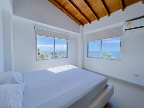 科韦尼亚斯Condominio bahia blanca的一间白色卧室,设有2个窗户和1张床