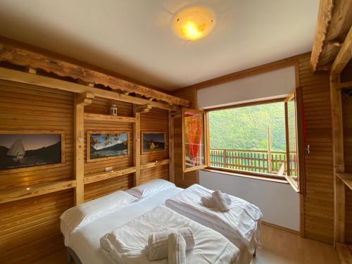 皮耶韦迪莱德罗Ca' Romantica - Ledro House的一间卧室配有一张带木墙和窗户的床。