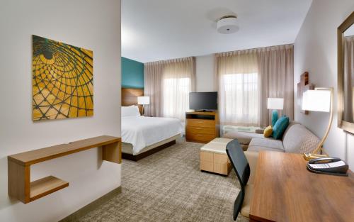 盖恩斯维尔Staybridge Suites - Gainesville I-75, an IHG Hotel的酒店客房带一张床铺、一张书桌和一间卧室